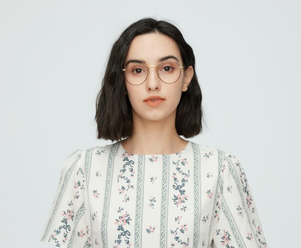 Portrait of a young woman in a floral dress and glasses, studio shot.